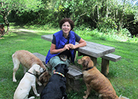 Mairead at a picnic bench surrounded by happy dogs sitting in a circle. Copyright You And Your Dog